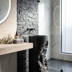 Torn layered black artificial stone freestanding cylinder pedestal basin 1335 with fine horizontal ribbon striations and dramatic matte black torn fractured exposed section
