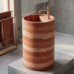 Close-up of handcrafted rammed earth horizontal stripe banding in terracotta blush and rust tones on Eclipse concrete freestanding cylinder pedestal washbasin