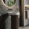 Muniq artificial stone pedestal basin 1315 450x860mm showing deep mocha bronze fluted cylinder pedestal with clean brilliant white round bowl in warm luxury bathroom washbasin