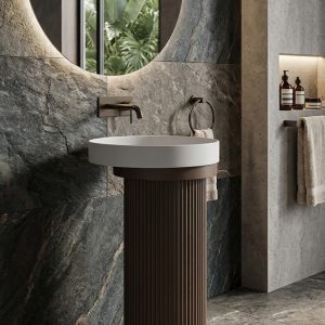 Muniq artificial stone pedestal basin 1315 450x860mm showing deep mocha bronze fluted cylinder pedestal with clean brilliant white round bowl in warm luxury bathroom washbasin