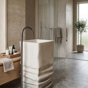 Muniq artificial stone pedestal basin 1329 400x850mm showing warm cream square monolith with organic horizontal sandstone strata layered texture on lower pedestal and smooth integrated square bowl
