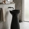 Noir Flute freestanding artificial stone pedestal basin featuring a matte black finish, sculptural hourglass silhouette, and deep vertical fluted detailing