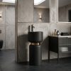 Matte black artificial stone freestanding mushroom pedestal basin with rounded black bowl polished bronze connecting ring and bronze floor faucet in dark concrete bathroom