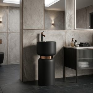 Matte black artificial stone freestanding mushroom pedestal basin with rounded black bowl polished bronze connecting ring and bronze floor faucet in dark concrete bathroom