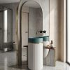 Artificial stone freestanding fluted pedestal basin 1301 with deep teal bowl gold connecting ring and white vertically fluted column in luxury bathroom with gold arch mirror