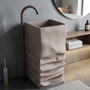 Muniq artificial stone pedestal basin 1329 400x850mm showing warm cream square monolith with organic horizontal sandstone strata layered texture on lower pedestal and smooth integrated square bowl