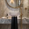 Muniq matte black resin freestanding basin with fluted crystal resin bowl and brushed gold ring in five star hotel luxury bathroom with marble wall cladding gold floor tap and round gold mirror