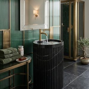 Close-up of precision vertical reeded fluting and dramatic bold white calcite veining on Muniq fluted Nero Marquina black marble cylinder freestanding pedestal basin