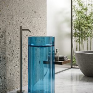Royal Blue freestanding transparent resin basin 7103 with full-height fluted cylinder form glowing vivid royal blue with chrome floor faucet in white bathroom