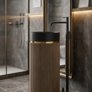 Muniq artificial stone pedestal basin with sand beige fluted cylinder pedestal matte black bowl and gold ring accent in moody luxury bathroom with brass framed mirror and dark stone walls