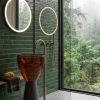 Freestanding amber cognac transparent resin bowl basin 7104 with wide glowing amber bowl on dark charcoal cone pedestal and slim gold floor faucet in luxury bathroom with mountain view