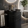 Muniq freestanding fluted Nero Marquina marble basin black stone cylinder pedestal sink with bold white calcite veining and brushed gold wall tap in luxury dark bathroom
