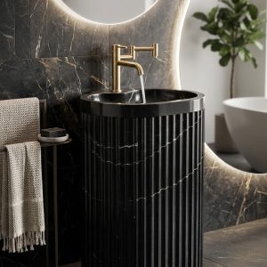 Muniq freestanding fluted Nero Marquina marble basin black stone cylinder pedestal sink with bold white calcite veining and brushed gold wall tap in luxury dark bathroom