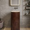 Muniq artificial stone pedestal basin with deep walnut wood effect fluted cylinder pedestal and white terrazzo bowl rim in warm biophilic bathroom with travertine walls and brass mirror