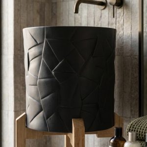 Close-up view of geometric sculpted texture on a luxury matte black composite stone vessel basin.