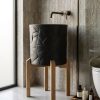 Matte black composite stone vessel basin featuring geometric faceted texture mounted on a minimalist solid wood stand.