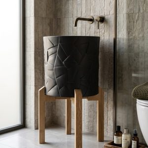 Matte black composite stone vessel basin featuring geometric faceted texture mounted on a minimalist solid wood stand.