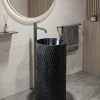 Black composite stone freestanding chiselled pedestal basin with raw hand-textured exterior and polished dark interior bowl in warm stone contemporary bathroom