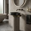 Luxury black stone vessel basin mounted on a wood-textured cylindrical pedestal with metallic accent ring in a modern designer bathroom.