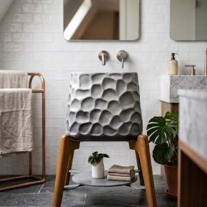 Composite stone vessel basin featuring a sculpted pebble texture exterior mounted on a designer wooden stand with storage shelf.