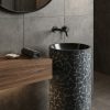 Black composite stone freestanding basin featuring geometric mosaic texture and contemporary cylindrical pedestal design.